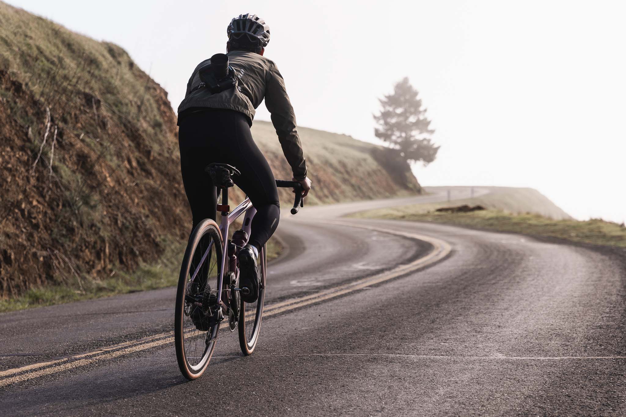 Man riding a road bike up a hill in fog